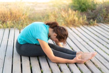 Dışarıda yoga yapan genç bir kadın.