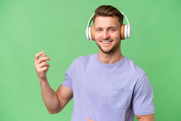 Young Blonde Caucasian Man Isolated Background Listening Music Doing Guitar — Stock Photo, Image