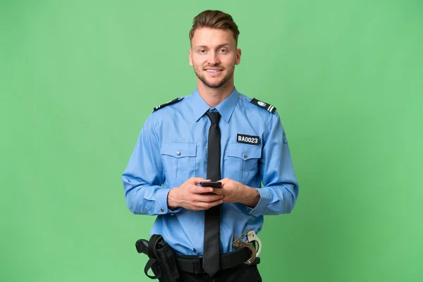 Joven Policía Sobre Antecedentes Aislados Enviando Mensaje Con Móvil —  Fotos de Stock