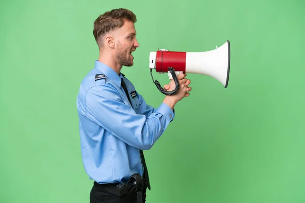 Young police man over isolated background shouting through a megaphone