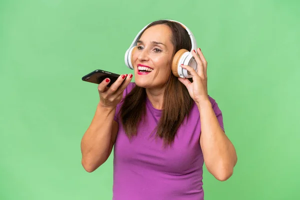 Medelålders Kaukasiska Kvinna Över Isolerad Bakgrund Lyssna Musik Med Mobil — Stockfoto