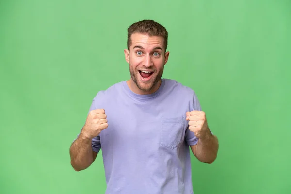 stock image Young handsome caucasian man isolated on green chroma background celebrating a victory in winner position