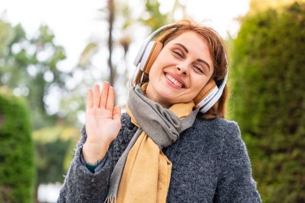 Μελαχρινή Γυναίκα Ακούει Μουσική Ακουστικά Εξωτερικούς Χώρους Χαιρετισμό Χέρι Χαρούμενη — Φωτογραφία Αρχείου
