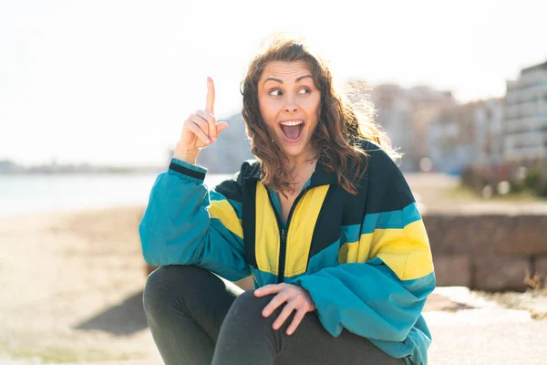 屋外で指を持ち上げながら解決策を実現しようとする若いスポーツ女性 — ストック写真