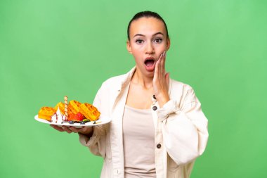 Genç bir Arap kadının, yalıtılmış arka planda waffle tutması şaşkınlık ve şok etkisi yarattı.