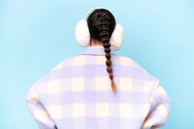 Arka planda mavi arka planda izole edilmiş kışlık manşet giyen genç bir Arap kadın.