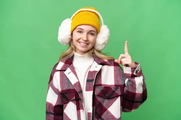 年轻的英国女人披着冬衣 站在与世隔绝的背景上 伸出一个手指 表示她是最棒的 — 图库照片