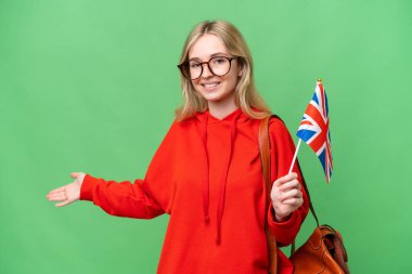 Young hispanic woman holding an United Kingdom flag over isolated background extending hands to the side for inviting to come