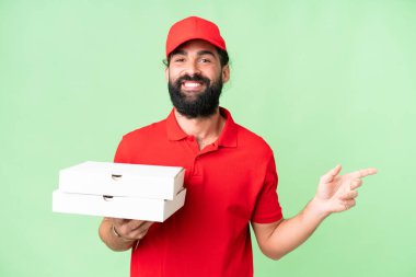 Pizza teslimatçısı üniformalı adam izole edilmiş krom anahtar arka planında pizza kutuları topluyor.