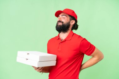 İş üniformalı bir pizzacı, izole edilmiş krom anahtar arka planda pizza kutularını topluyor. Çabaladığı için sırt ağrısı çekiyor.