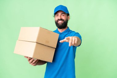 Teslimat beyaz adam izole edilmiş krom anahtar arka plan mutlu bir ifadeyle ön tarafı işaret ediyor
