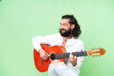 Young man with beard with guitar over isolated chroma key background