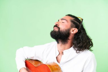 Young man with beard with guitar over isolated chroma key background