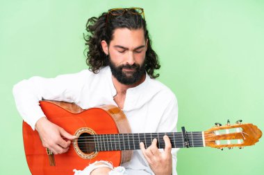 Young man with beard with guitar over isolated chroma key background