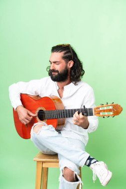 Young man with beard with guitar over isolated chroma key background