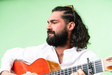 Young man with beard with guitar over isolated chroma key background