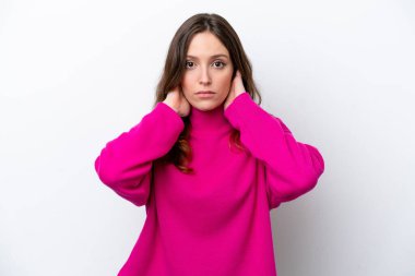 Beyaz arka planda izole edilmiş genç beyaz kadın hayal kırıklığına uğramış ve kulaklarını kapatmış.