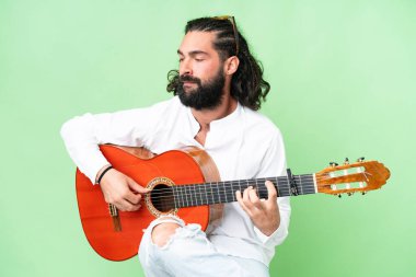 Young man with beard with guitar over isolated chroma key background
