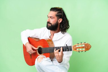 Young man with beard with guitar over isolated chroma key background