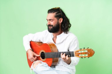 Young man with beard with guitar over isolated chroma key background