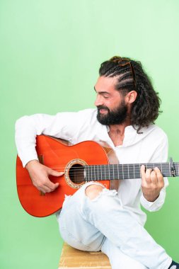 Young man with beard with guitar over isolated chroma key background