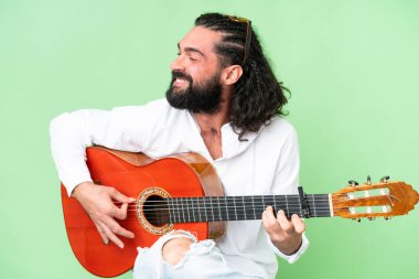 Young man with beard with guitar over isolated chroma key background