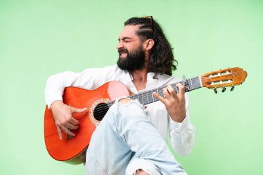 Young man with beard with guitar over isolated chroma key background