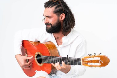 Young man with beard playing guitar on white background