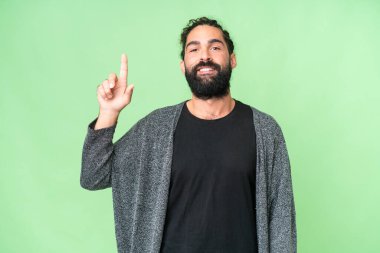 Young man with beard over isolated chroma key background pointing up a great idea