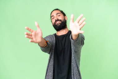 Sakallı genç adam izole edilmiş krom anahtar geçmişi ile sunar ve davet eder.