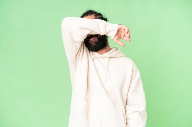 Sakallı genç adam izole edilmiş krom anahtar arka planda gözlerini elleriyle kapatıyor.