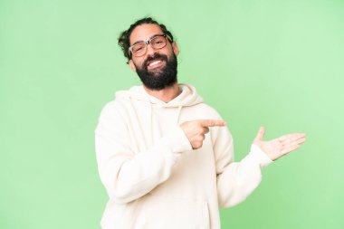 İzole edilmiş krom arka planda sakallı genç bir adam bir ilan vermek için fotokopi makinesini avucunun içinde tutuyor.