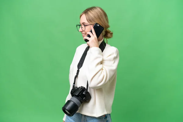 孤立した背景の上に若い写真家英語の女性誰かと携帯電話との会話を保つ — ストック写真