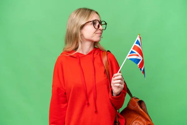 年轻的惊慌失措的女人举着英国国旗 背景偏僻 向侧面望去 — 图库照片
