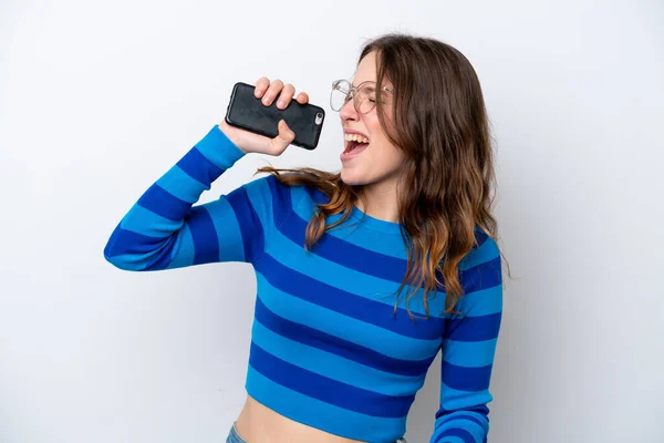 携帯電話と歌を使って白人の背景に孤立した若い白人女性 — ストック写真