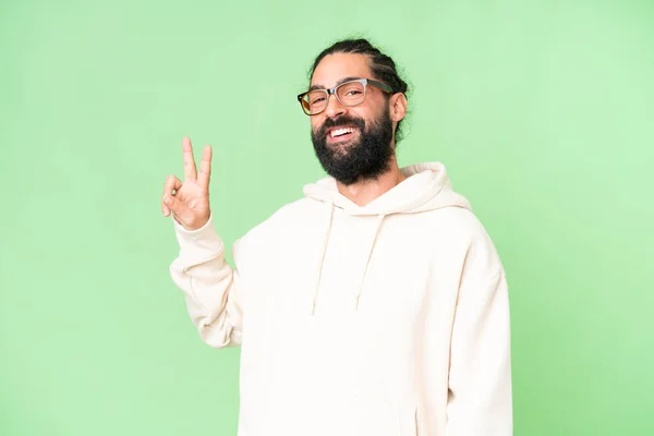 stock image Young man with beard over isolated chroma key background smiling and showing victory sign