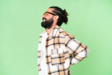 Young man with beard over isolated chroma key background suffering from backache for having made an effort