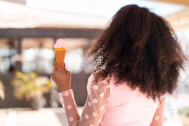 Arka tarafta kornet dondurmalı genç Afrikalı Amerikalı kadın.