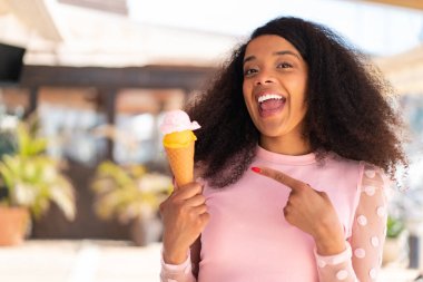 Açık havada kornet dondurmalı genç Afrikalı Amerikalı kadın.