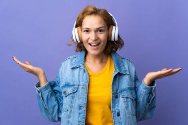 Mor arka planda izole edilmiş genç Gürcü kadın şaşırdı ve müzik dinliyor