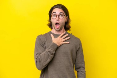Caucasian handsome man isolated on yellow background surprised and shocked while looking right