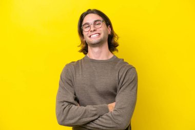 Sarı arka planda izole edilmiş, kolları çapraz ve ileriye bakan beyaz yakışıklı bir adam.