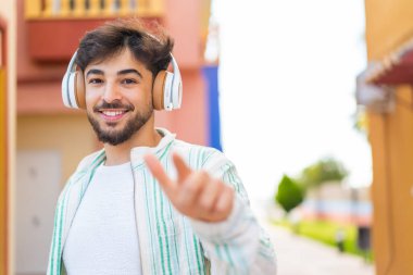 Açık havada müzik dinleyen yakışıklı bir Arap.