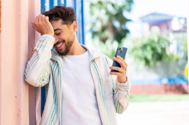 Açık havada cep telefonu kullanan yakışıklı bir Arap bir şeyi fark etti ve çözümü arıyor.