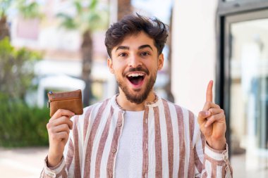 Dışarıda cüzdan tutan yakışıklı bir Arap harika bir fikri işaret ediyor.