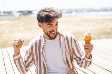 Açık havada kornet dondurmalı yakışıklı bir Arap zaferi kutluyor.