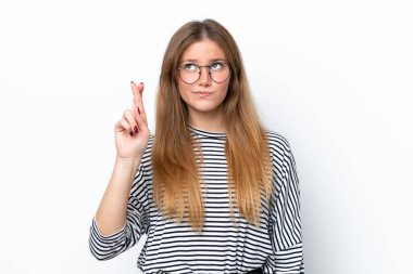 Beyaz arka planda izole edilmiş beyaz tenli genç bir kadın parmaklarını çapraz yapıp en iyisini diliyor.