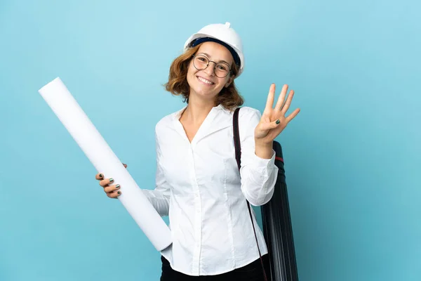 Young architect Georgian woman with helmet and holding blueprints over isolated background happy and counting four with fingers