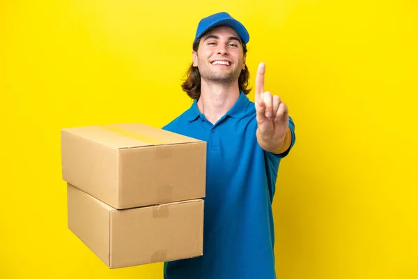 stock image Delivery handsome man isolated on yellow background showing and lifting a finger