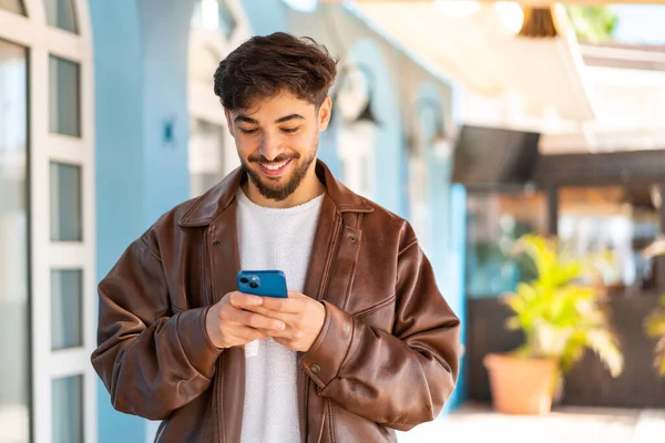 英俊的阿拉伯男子在户外用手机发短信或发电子邮件 — 图库照片